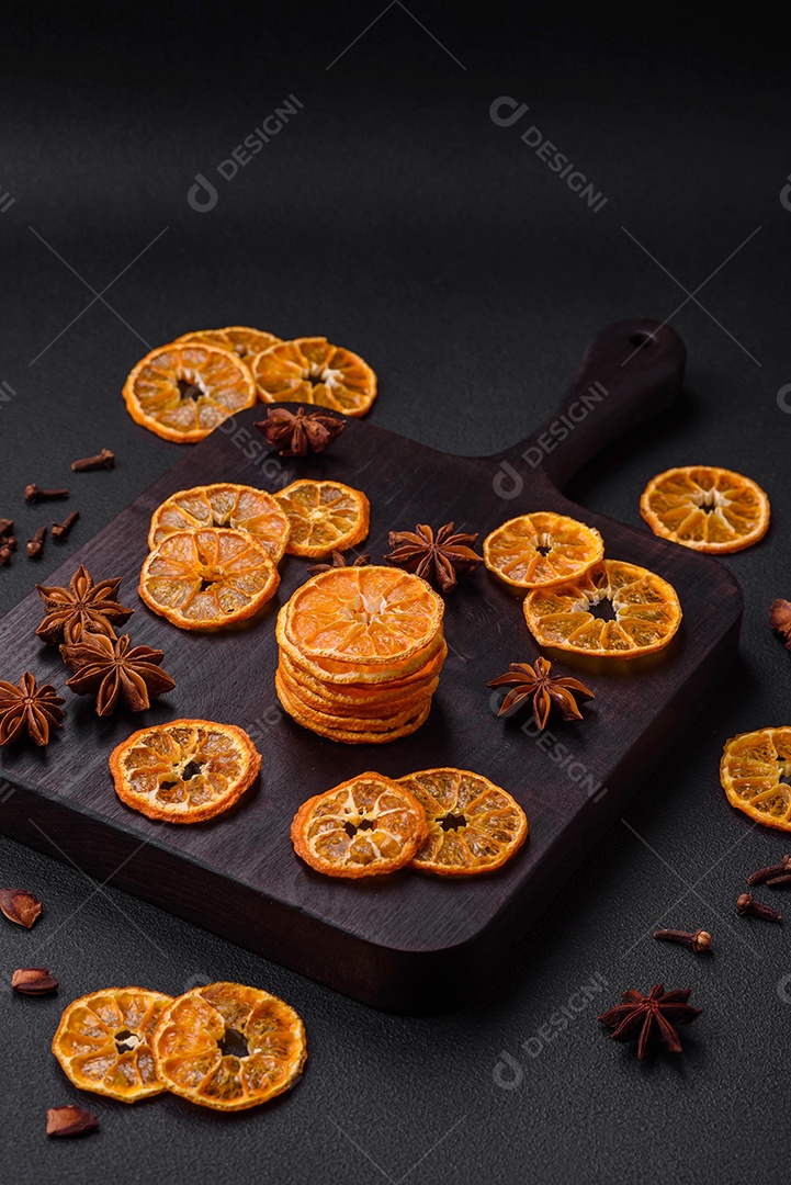 Fatias secas de forma redonda de tangerina de cor laranja brilhante sobre um fundo textural escuro