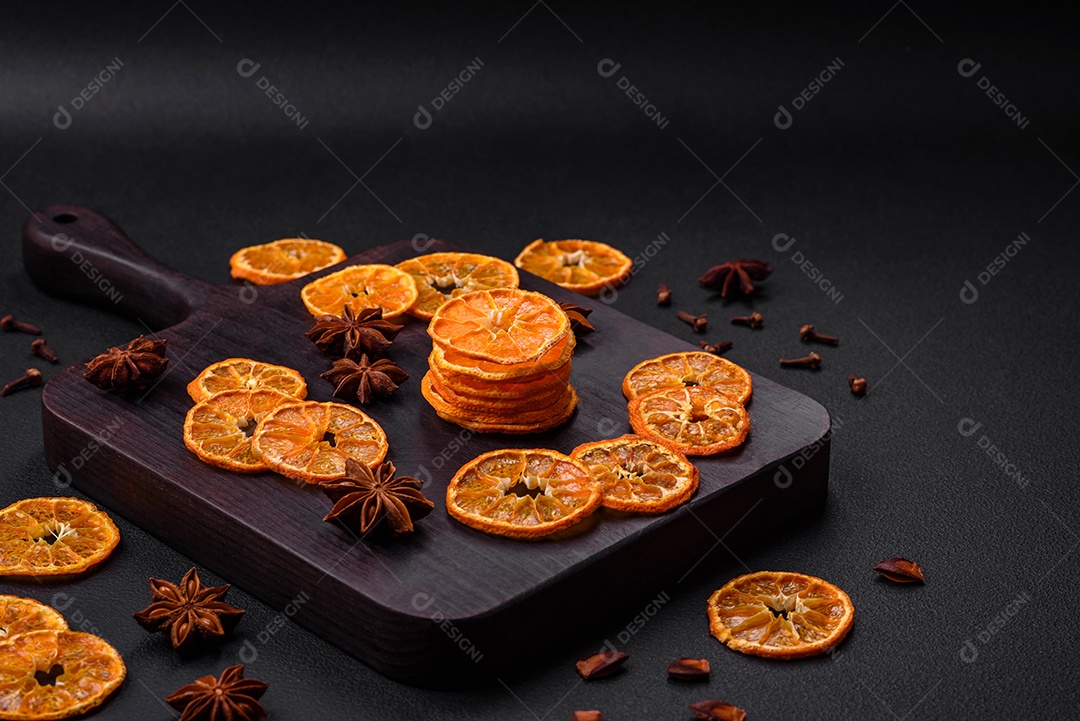 Fatias secas de forma redonda de tangerina de cor laranja brilhante sobre um fundo textural escuro