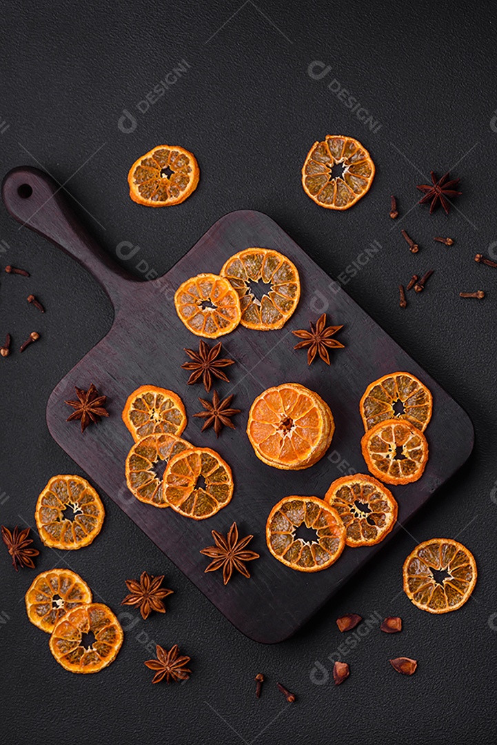 Fatias secas de forma redonda de tangerina de cor laranja brilhante sobre um fundo textural escuro