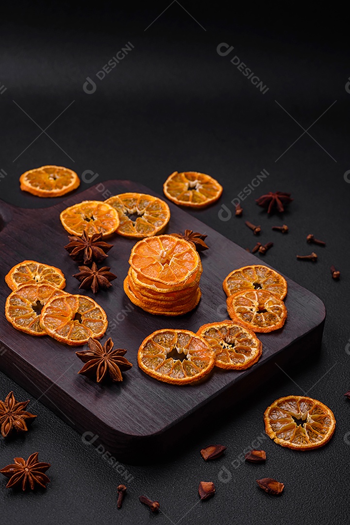 Fatias secas de forma redonda de tangerina de cor laranja brilhante sobre um fundo textural escuro