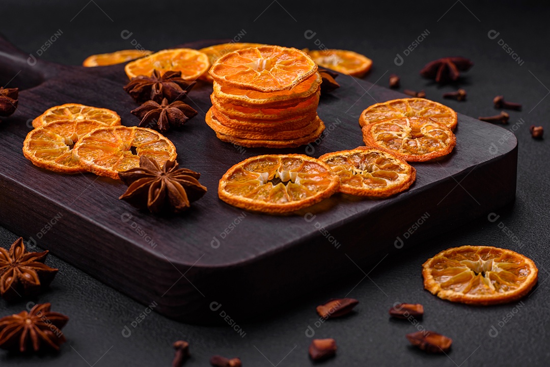 Fatias secas de forma redonda de tangerina de cor laranja brilhante sobre um fundo textural escuro