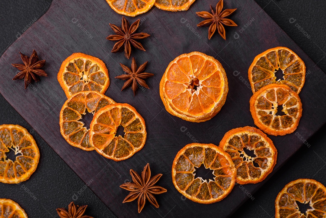 Fatias secas de forma redonda de tangerina de cor laranja brilhante sobre um fundo textural escuro