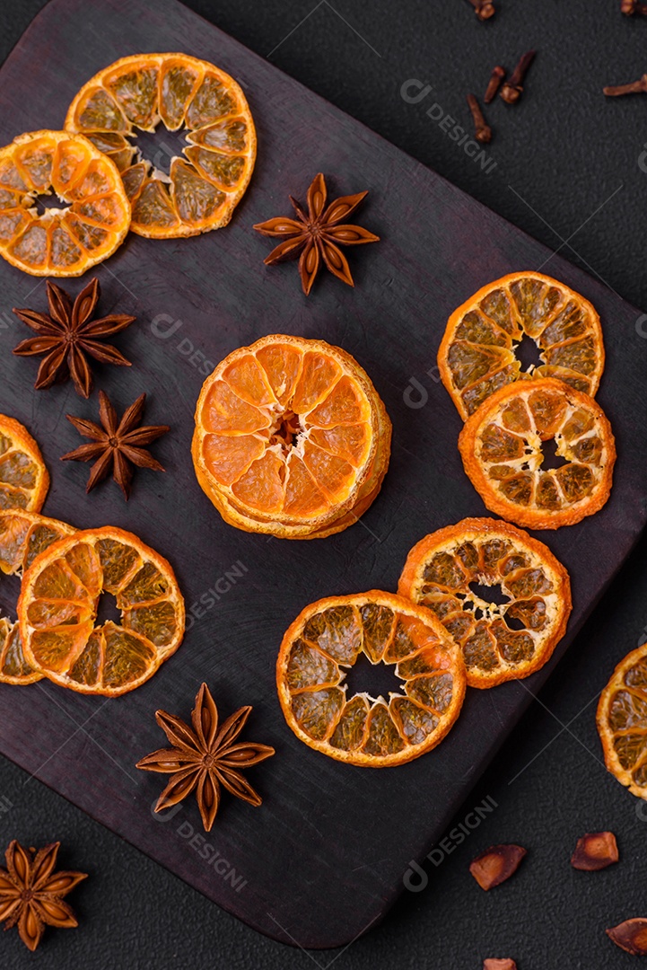 Fatias secas de forma redonda de tangerina de cor laranja brilhante sobre um fundo textural escuro