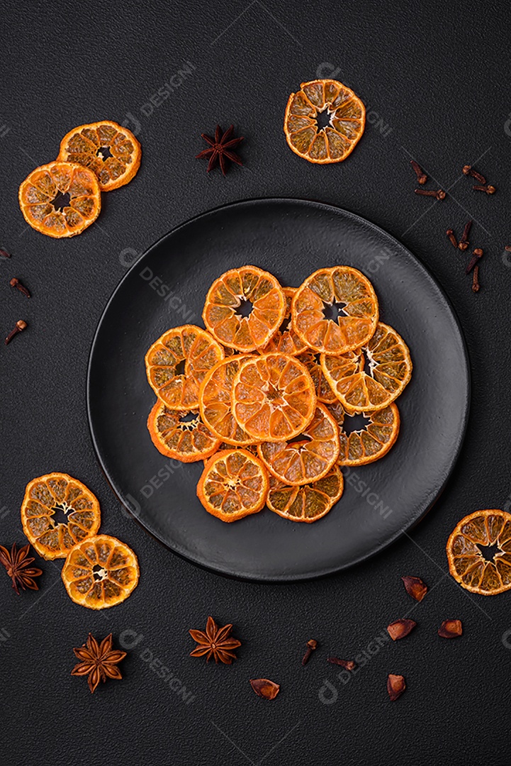 Fatias secas de forma redonda de tangerina de cor laranja brilhante sobre um fundo textural escuro