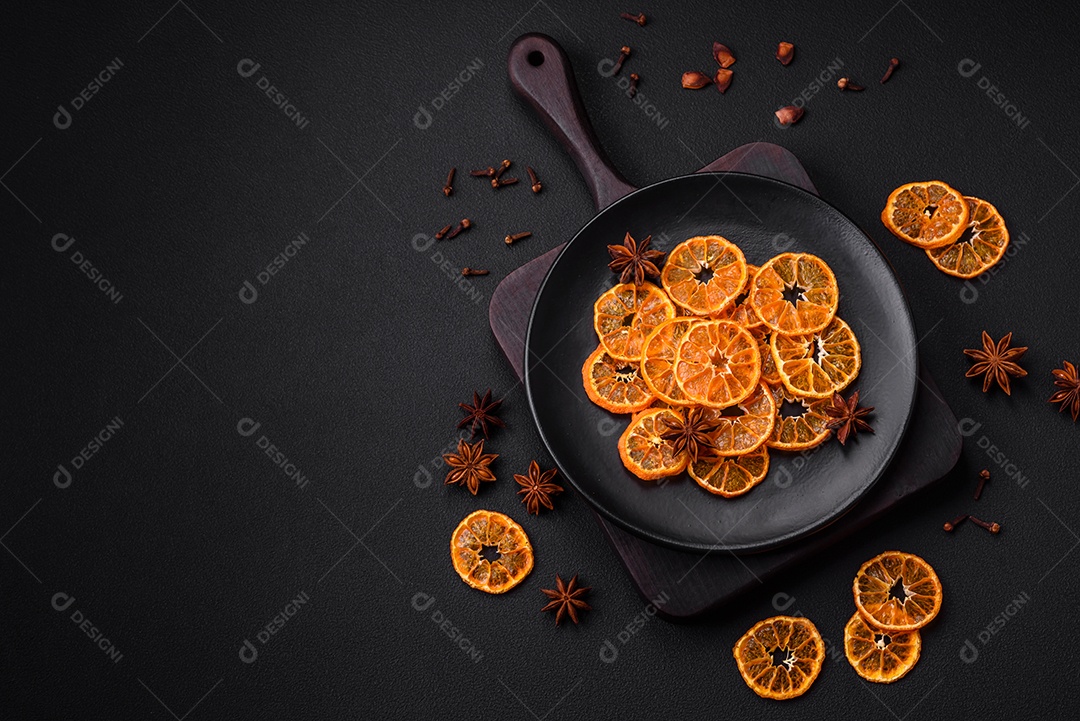 Fatias secas de forma redonda de tangerina de cor laranja brilhante sobre um fundo textural escuro