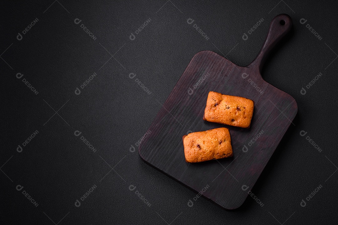 Deliciosos muffins de chocolate e fatias redondas secas de tangerina de cor laranja brilhante sobre um fundo textural escuro