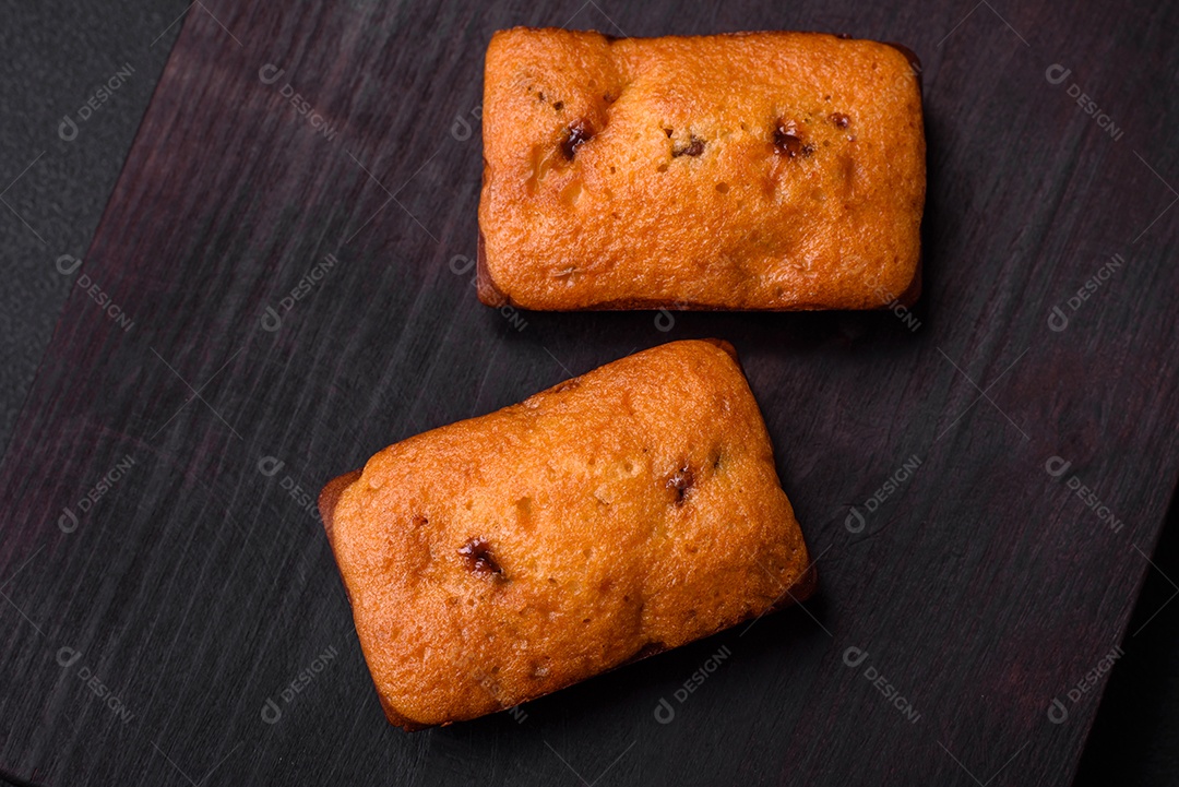Deliciosos muffins de chocolate e fatias redondas secas de tangerina de cor laranja brilhante sobre um fundo textural escuro