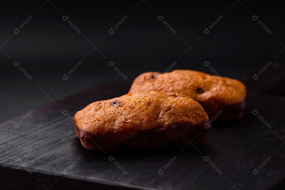 Deliciosos muffins de chocolate e fatias redondas secas de tangerina de cor laranja brilhante sobre um fundo textural escuro