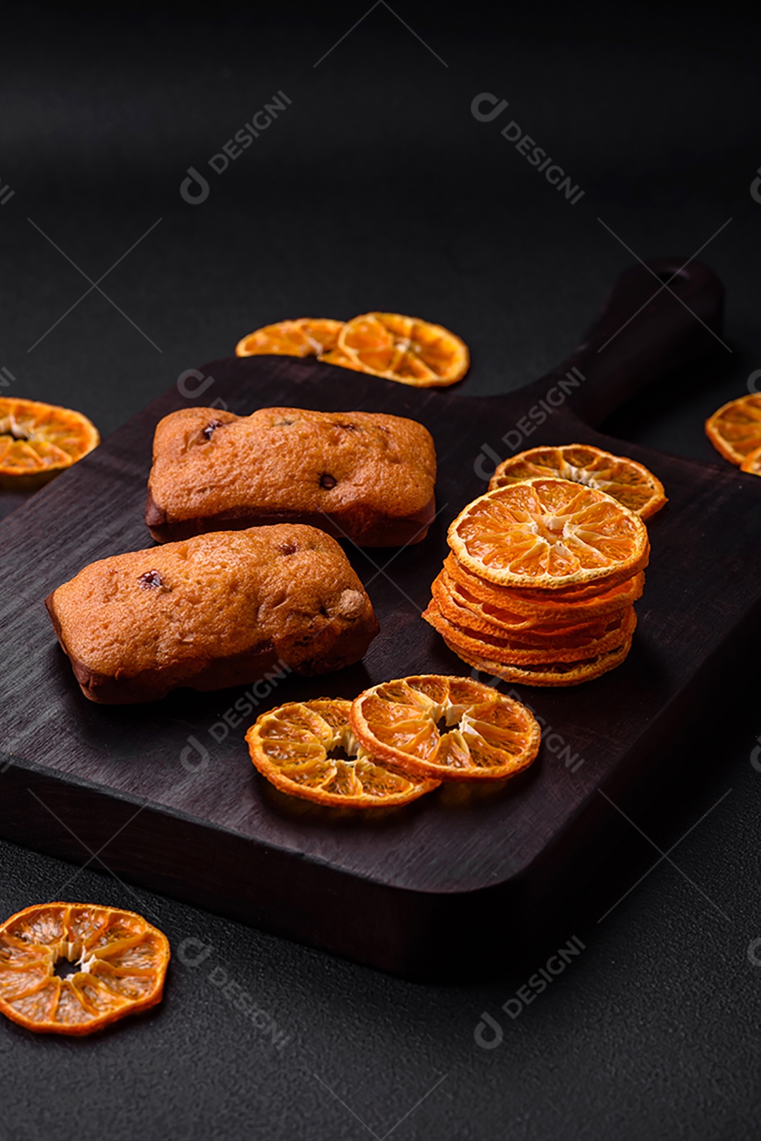 Deliciosos muffins de chocolate e fatias redondas secas de tangerina de cor laranja brilhante sobre um fundo textural escuro