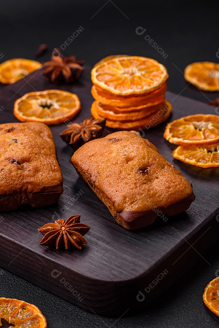 Deliciosos muffins de chocolate e fatias redondas secas de tangerina de cor laranja brilhante sobre um fundo textural escuro