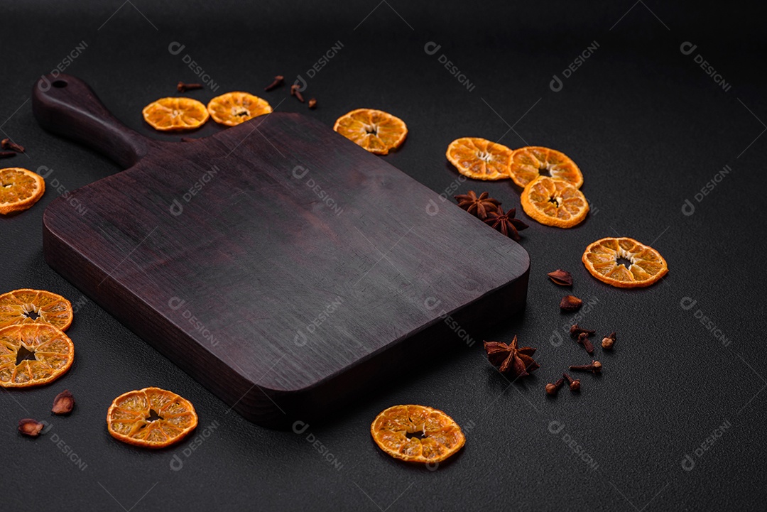 Fatias secas de forma redonda de tangerina de cor laranja brilhante sobre um fundo textural escuro