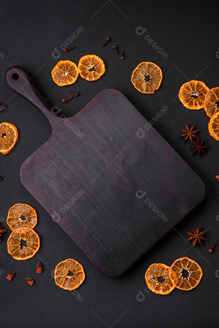 Fatias secas de forma redonda de tangerina de cor laranja brilhante sobre um fundo textural escuro