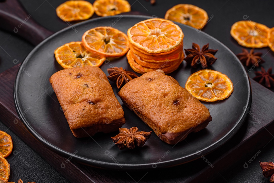 Deliciosos muffins de chocolate e fatias redondas secas de tangerina de cor laranja brilhante sobre um fundo textural escuro