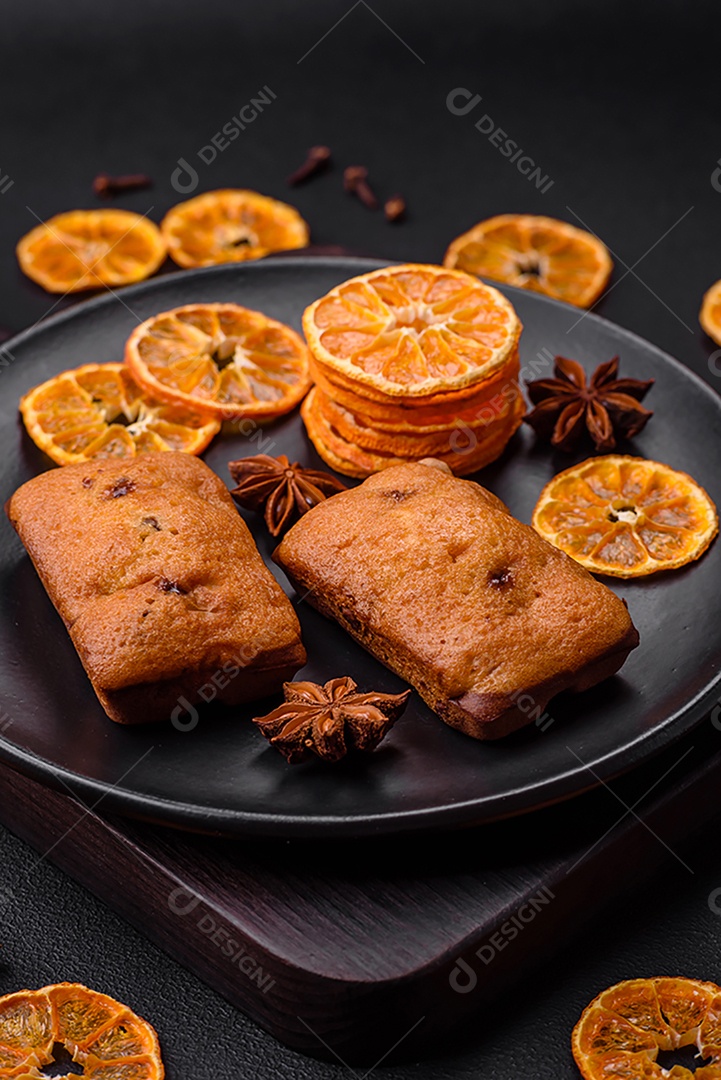 Deliciosos muffins de chocolate e fatias redondas secas de tangerina de cor laranja brilhante sobre um fundo textural escuro