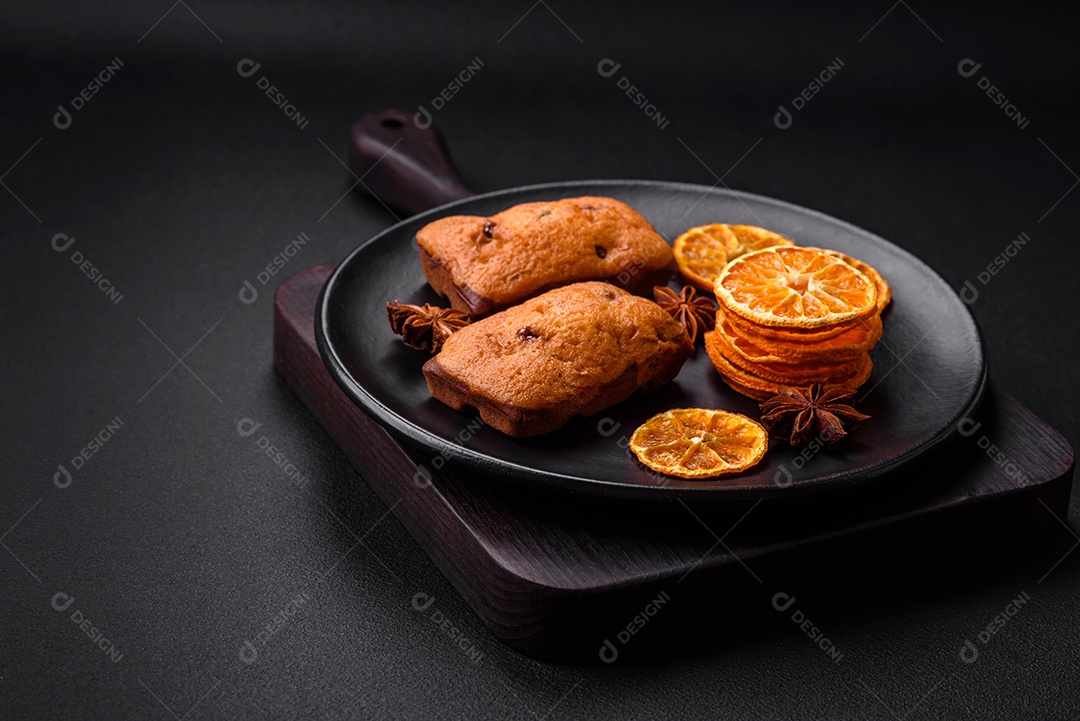 Deliciosos muffins de chocolate e fatias redondas secas de tangerina de cor laranja brilhante sobre um fundo textural escuro