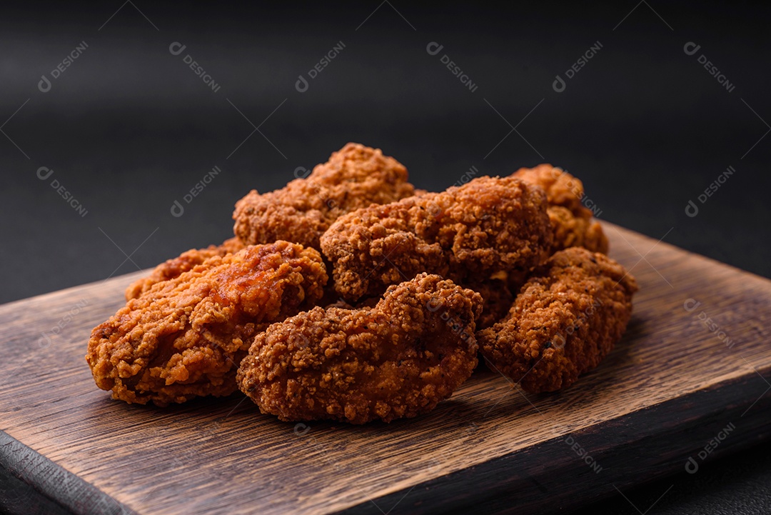 Deliciosas asas de frango empanadas crocantes grelhadas com especiarias e ervas em um fundo escuro de concreto