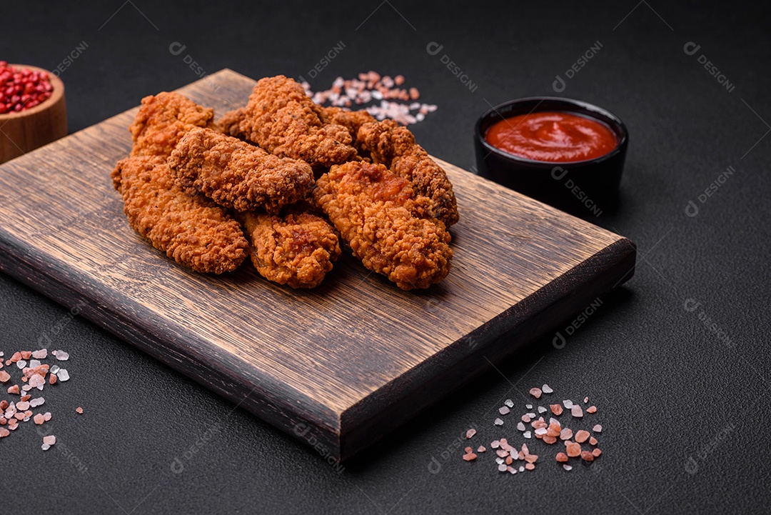 Deliciosas asas de frango empanadas crocantes grelhadas com especiarias e ervas em um fundo escuro de concreto