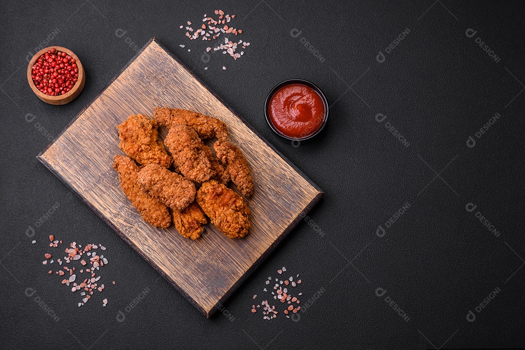Deliciosas asas de frango empanadas crocantes grelhadas com especiarias e ervas em um fundo escuro de concreto