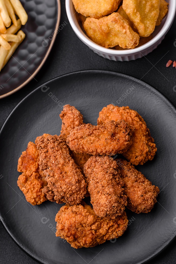 Deliciosas asas de frango empanadas crocantes grelhadas com especiarias e ervas em um fundo escuro de concreto