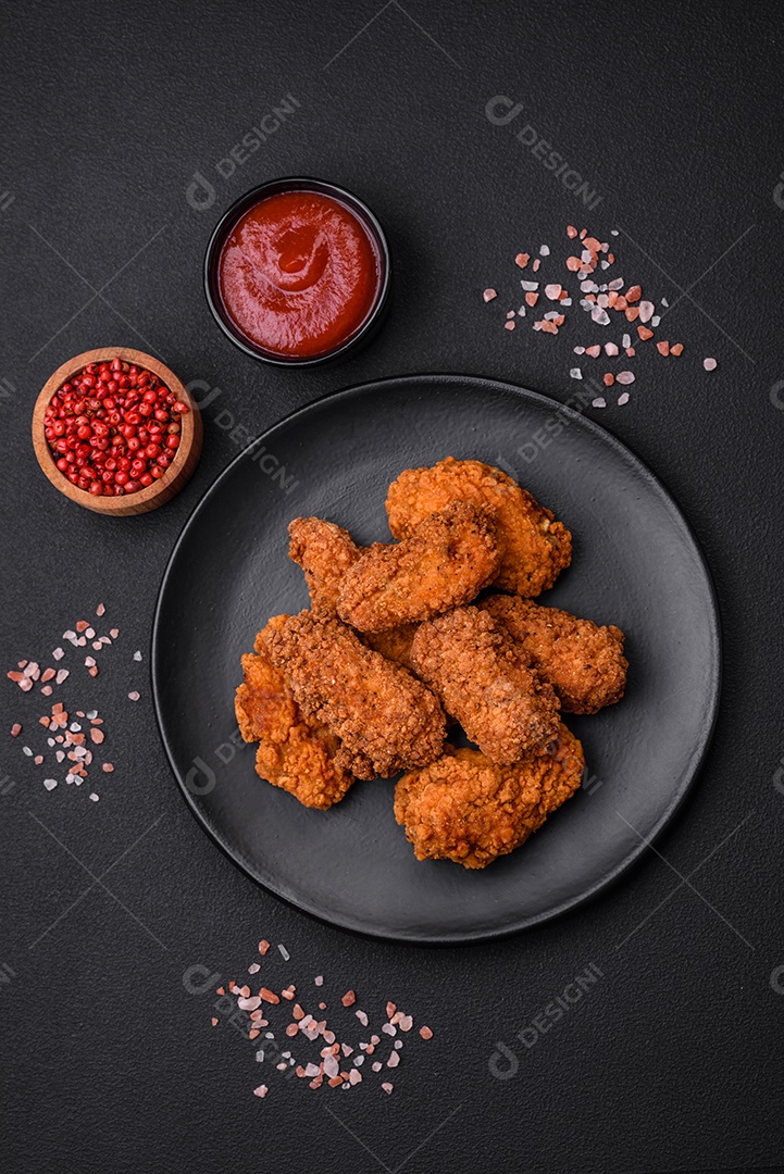 Deliciosas asas de frango empanadas crocantes grelhadas com especiarias e ervas em um fundo escuro de concreto