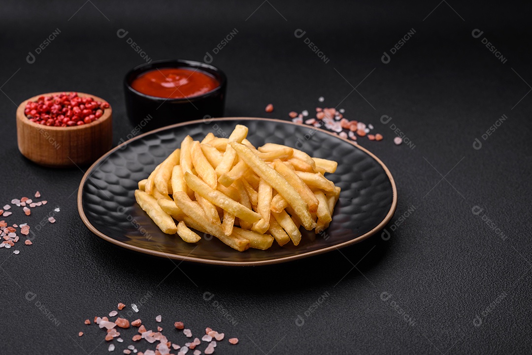Deliciosas batatas fritas crocantes com sal e especiarias em um fundo escuro de concreto. Alimentos não saudáveis, fast food