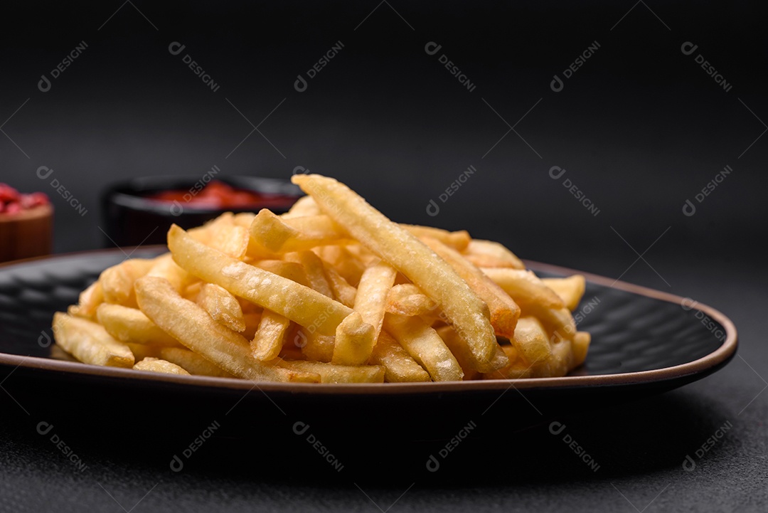 Deliciosas batatas fritas crocantes com sal e especiarias em um fundo escuro de concreto. Alimentos não saudáveis, fast food