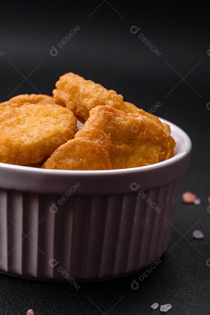 Deliciosos nuggets de frango crocantes com sal e especiarias em um fundo escuro de concreto. Comida lixo, fast-food