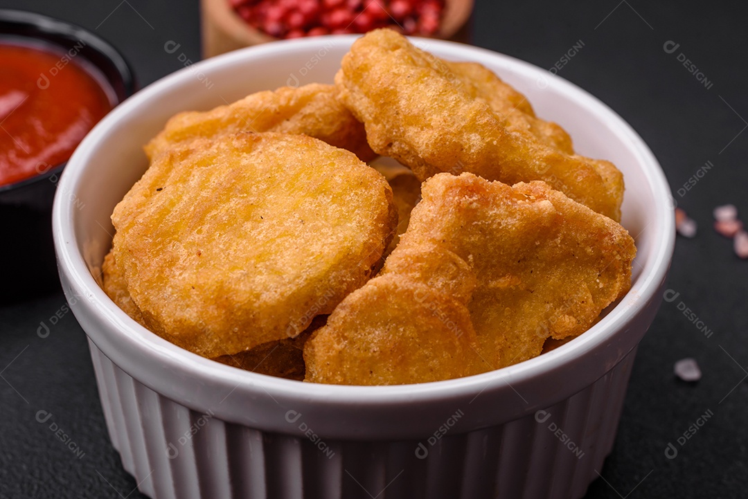 Deliciosos nuggets de frango crocantes com sal e especiarias em um fundo escuro de concreto. Comida lixo, fast-food