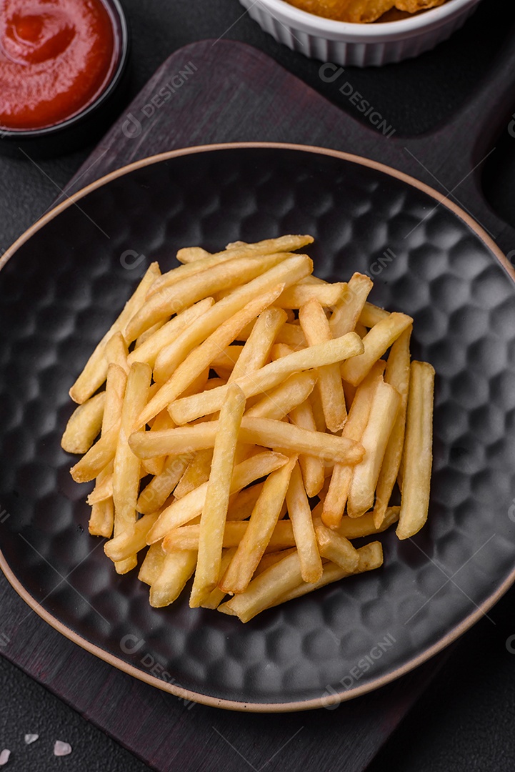Deliciosas batatas fritas crocantes com sal e especiarias em um fundo escuro de concreto. Alimentos não saudáveis, fast food