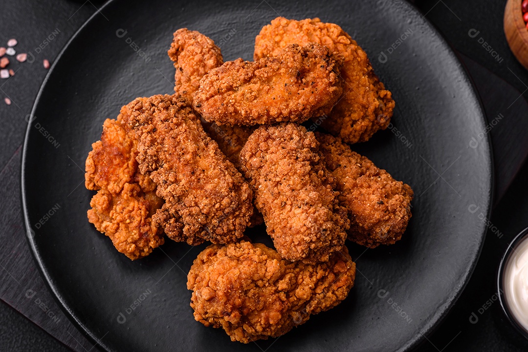 Deliciosas asas de frango empanadas crocantes grelhadas com especiarias e ervas em um fundo escuro de concreto