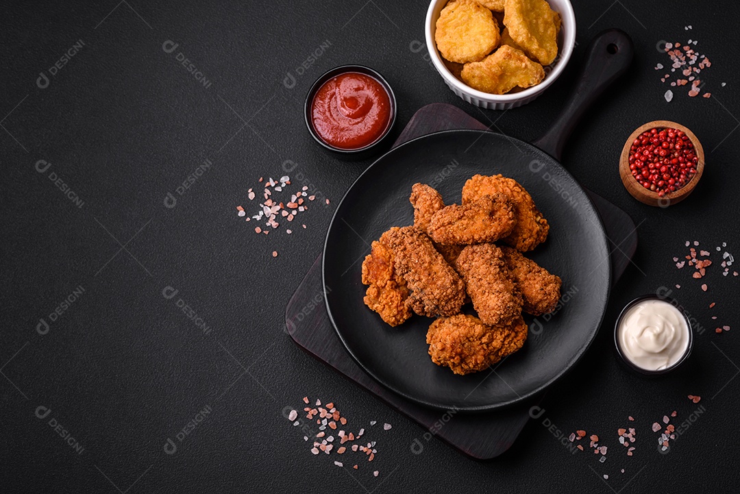 Deliciosas asas de frango empanadas crocantes grelhadas com especiarias e ervas em um fundo escuro de concreto