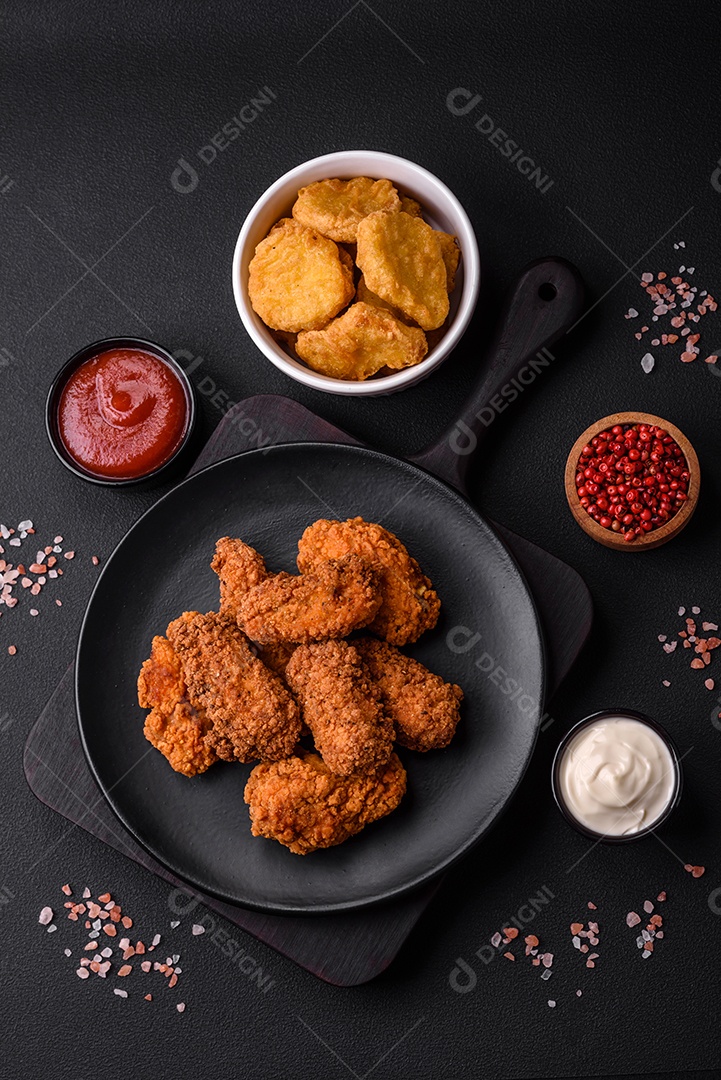 Deliciosas asas de frango empanadas crocantes grelhadas com especiarias e ervas em um fundo escuro de concreto
