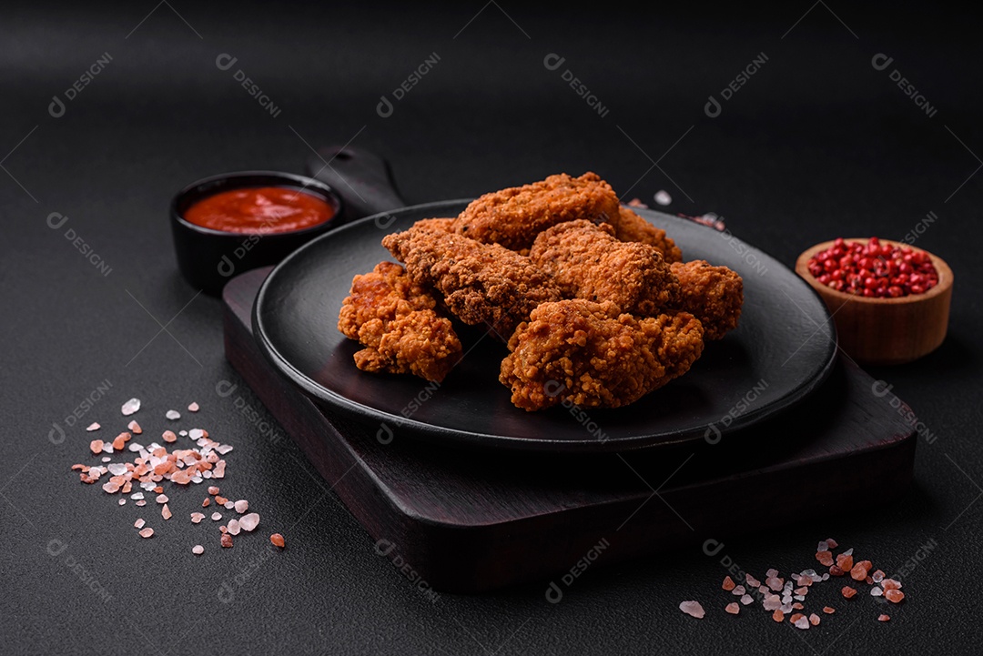 Deliciosas asas de frango empanadas crocantes grelhadas com especiarias e ervas em um fundo escuro de concreto