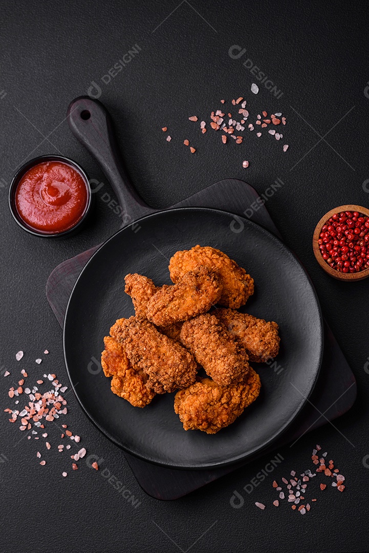 Deliciosas asas de frango empanadas crocantes grelhadas com especiarias e ervas em um fundo escuro de concreto