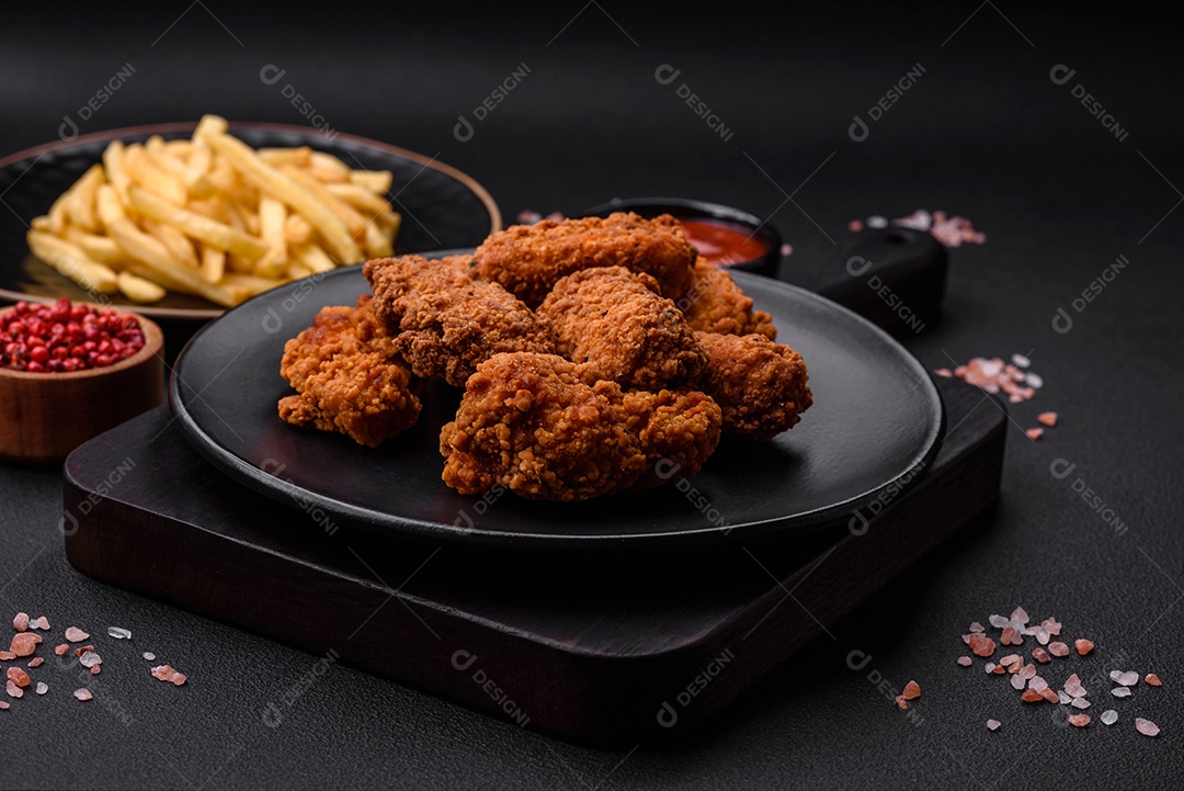 Deliciosas asas de frango empanadas crocantes grelhadas com especiarias e ervas em um fundo escuro de concreto