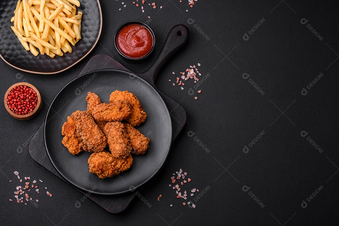 Deliciosas asas de frango empanadas crocantes grelhadas com especiarias e ervas em um fundo escuro de concreto