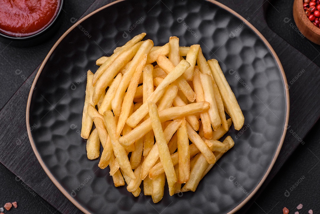 Deliciosas batatas fritas crocantes com sal e especiarias em um fundo escuro de concreto. Alimentos não saudáveis, fast food