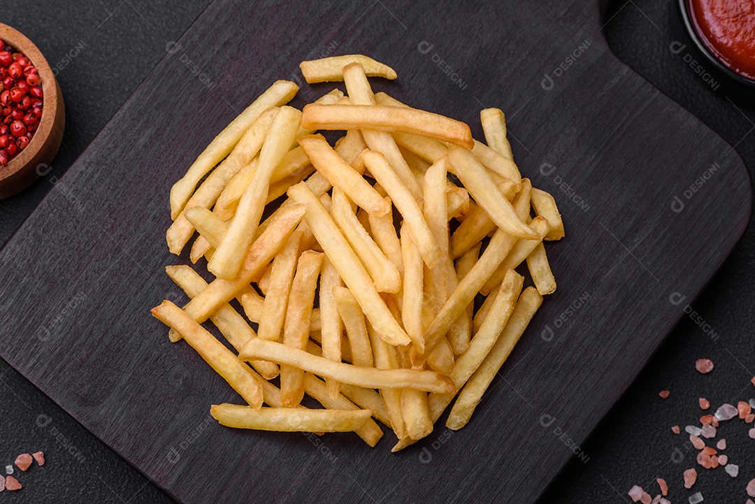 Deliciosas batatas fritas crocantes com sal e especiarias em um fundo escuro de concreto. Alimentos não saudáveis, fast food