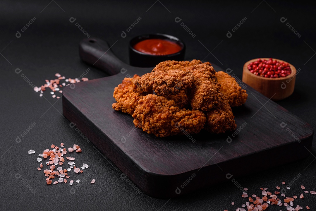 Deliciosas asas de frango empanadas crocantes grelhadas com especiarias e ervas em um fundo escuro de concreto