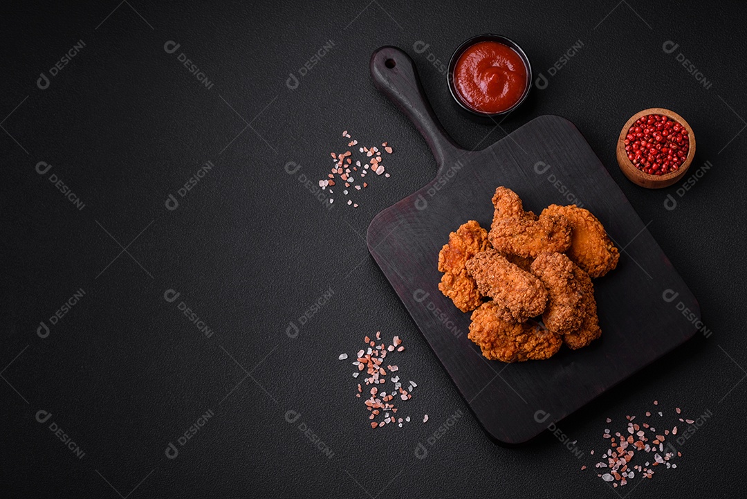 Deliciosas asas de frango empanadas crocantes grelhadas com especiarias e ervas em um fundo escuro de concreto