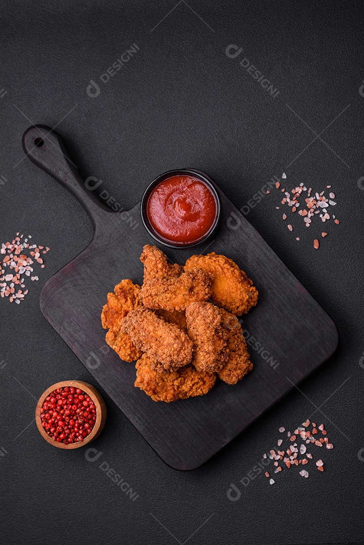 Deliciosas asas de frango empanadas crocantes grelhadas com especiarias e ervas em um fundo escuro de concreto