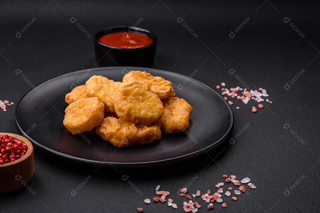 Deliciosos nuggets de frango crocantes com sal e especiarias em um fundo escuro de concreto. Comida lixo, fast-food