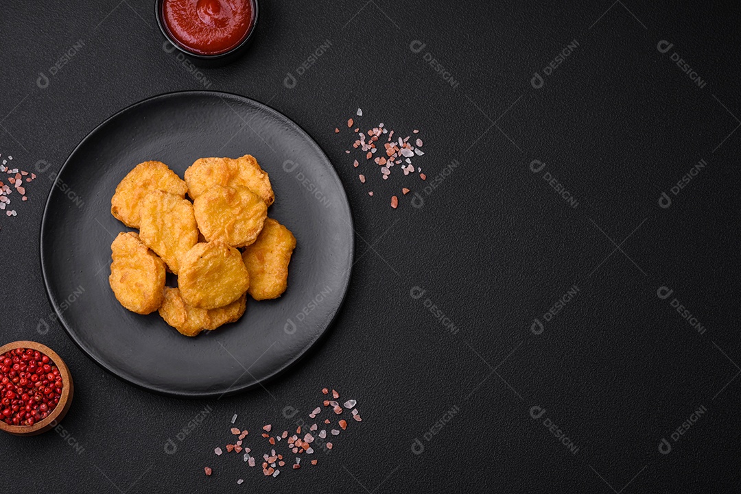 Deliciosos nuggets de frango crocantes com sal e especiarias em um fundo escuro de concreto. Comida lixo, fast-food