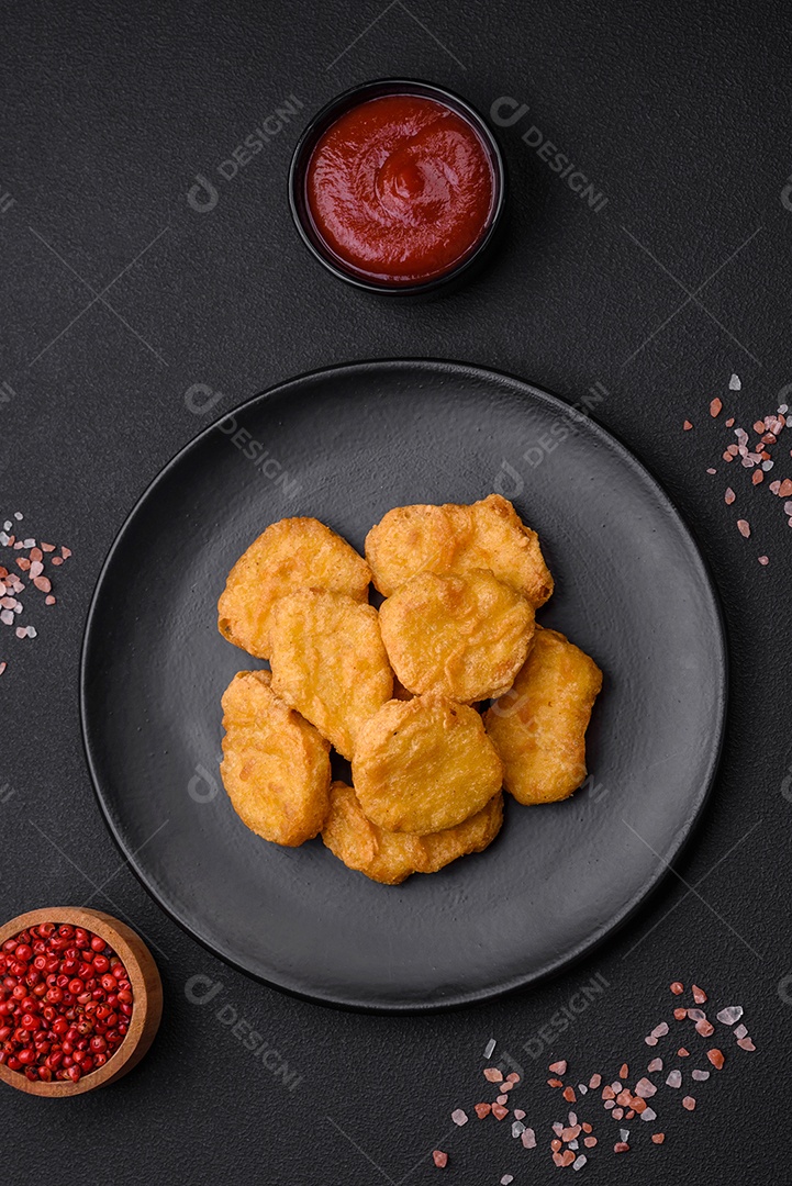 Deliciosos nuggets de frango crocantes com sal e especiarias em um fundo escuro de concreto. Comida lixo, fast-food