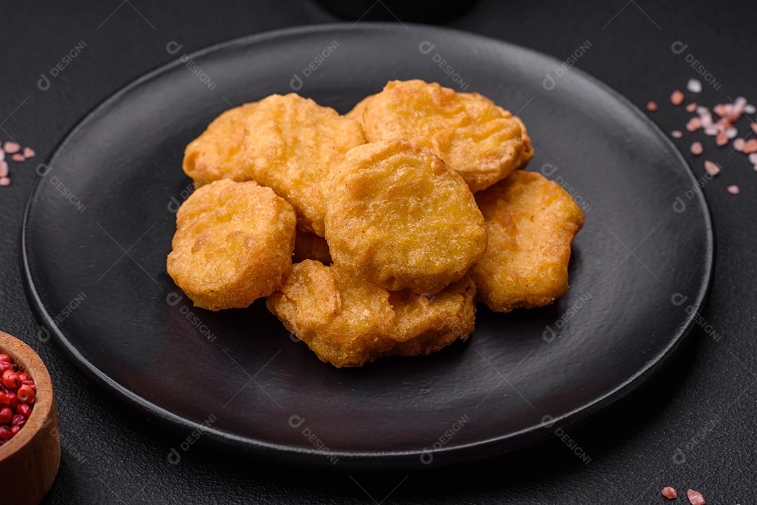 Deliciosos nuggets de frango crocantes com sal e especiarias em um fundo escuro de concreto. Comida lixo, fast-food