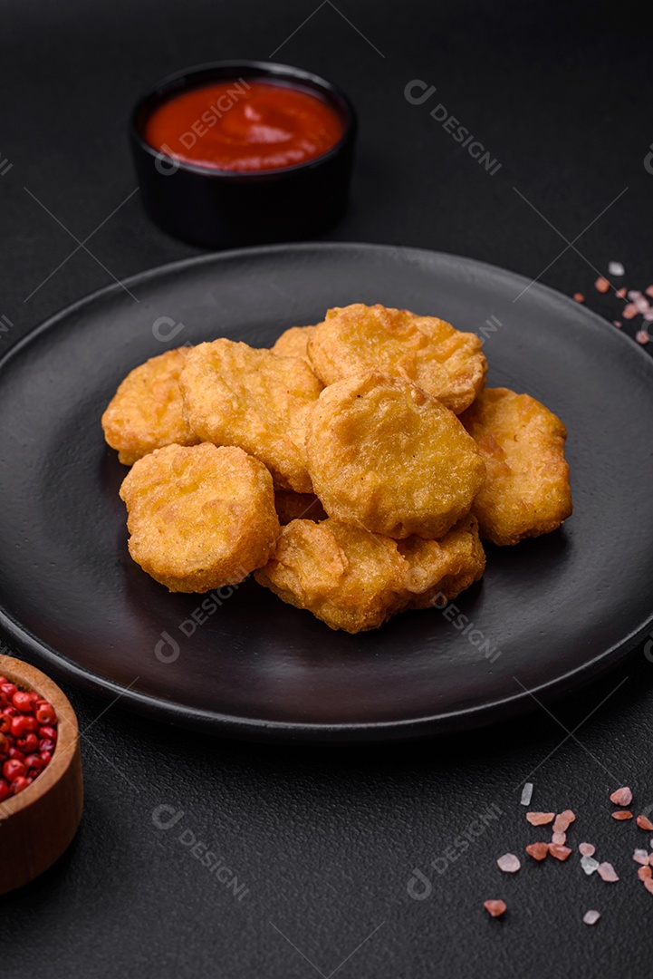 Deliciosos nuggets de frango crocantes com sal e especiarias em um fundo escuro de concreto. Comida lixo, fast-food