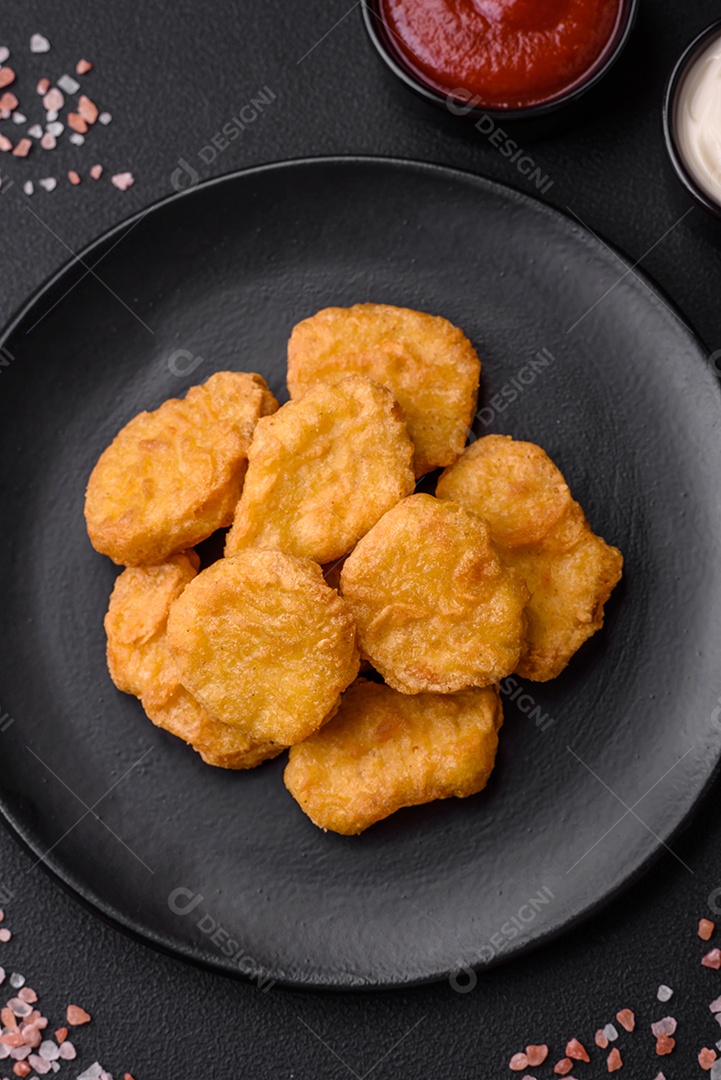 Deliciosos nuggets de frango crocantes com sal e especiarias em um fundo escuro de concreto. Comida lixo, fast-food