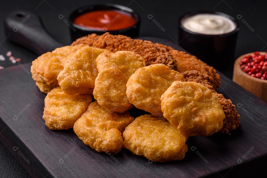 Deliciosos nuggets de frango crocantes com sal e especiarias em um fundo escuro de concreto. Comida lixo, fast-food