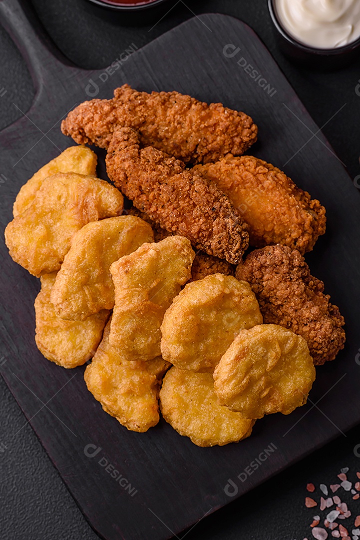 Deliciosos nuggets de frango crocantes com sal e especiarias em um fundo escuro de concreto. Comida lixo, fast-food