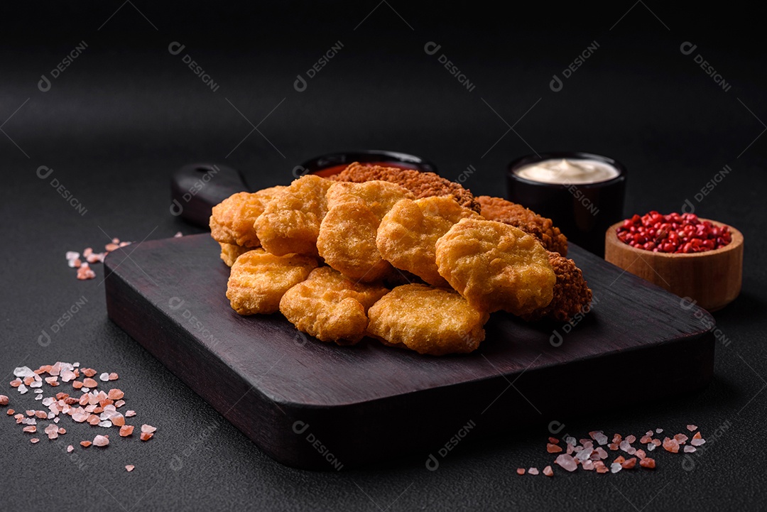 Deliciosos nuggets de frango crocantes com sal e especiarias em um fundo escuro de concreto. Comida lixo, fast-food